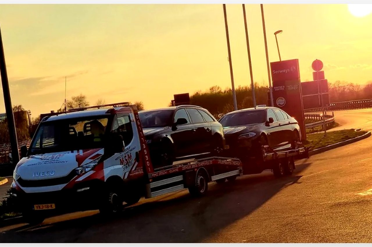 Bergingswagen met twee auto's op de oplegger bij zonsondergang