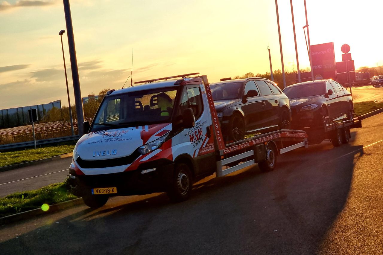 Twee auto's op de oplegger bij zonsondergang